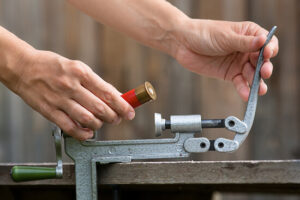 hands reloading cartridge by shotgun shell reloader